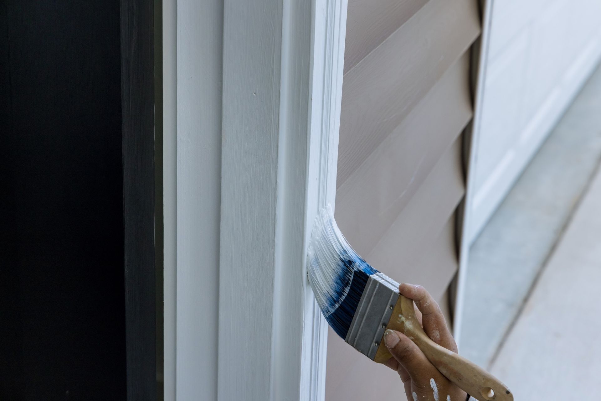 Hand painting white paint on door trim with a brush.