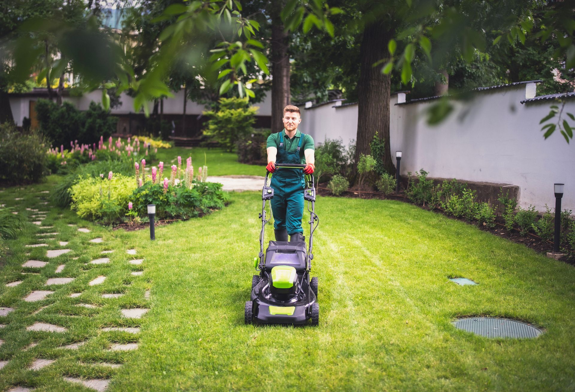 A man is mowing the lawn with a lawn mower on a sunny day, showcasing effective lawn care solutions. A man is mowing the lawn with a lawn mower on a sunny day, showcasing effective lawn care solutions.