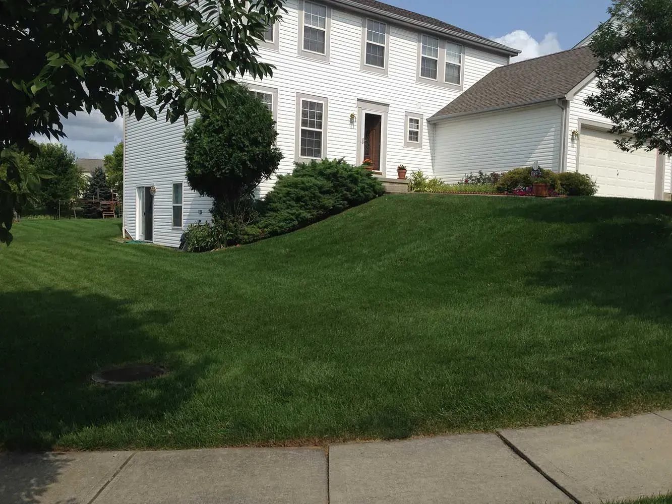 A two-story white house with a well-manicured lawn and sidewalk in front.