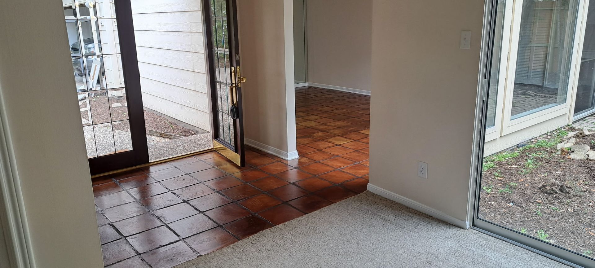 An empty room with a wooden floor and a sliding glass door.