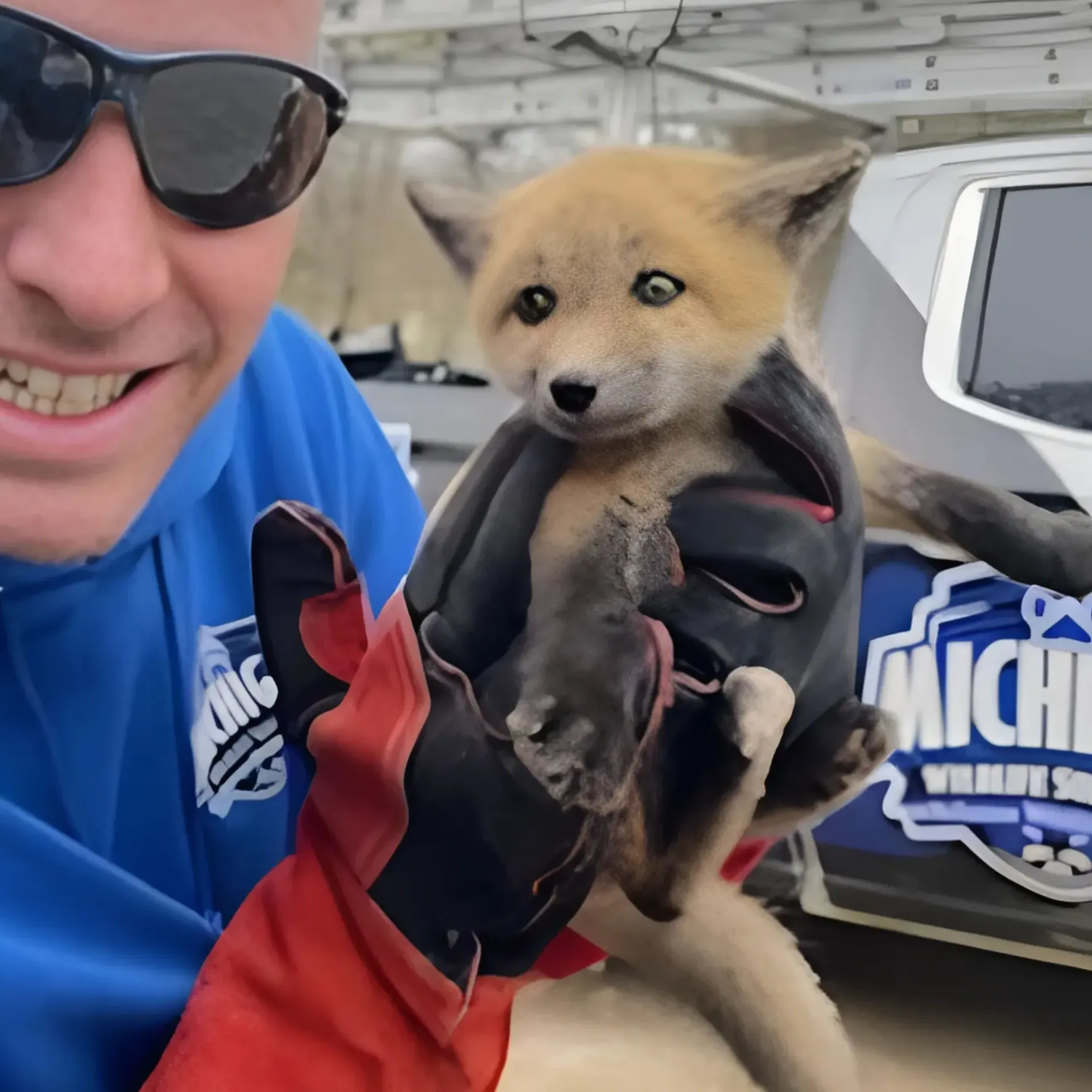 Michigan Wildlife Solutions - A man holding a puppy in front of a michigan vehicle