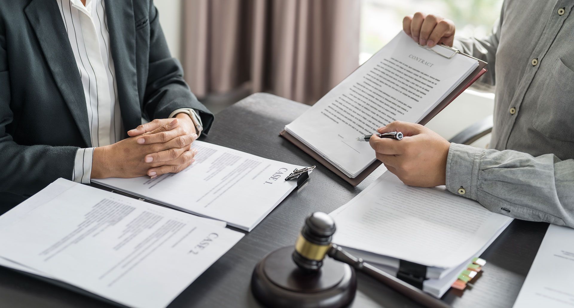Two people reviewing legal documents at a desk, gavel present.