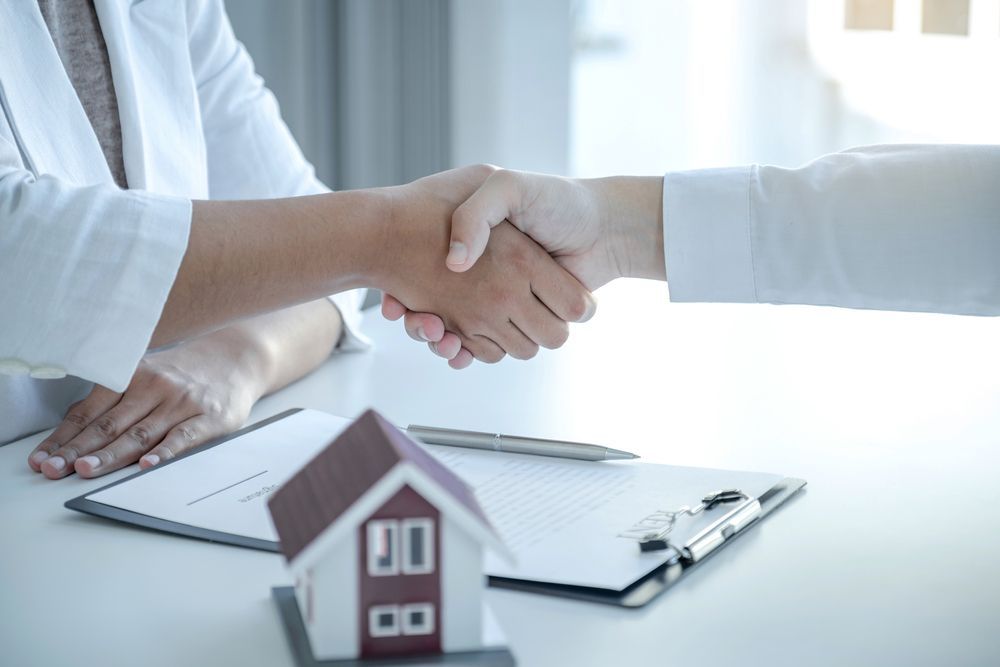 Two People in White Shirts Shake Hands Over a Document — Richardson Conveyancing In Sydney, NSW