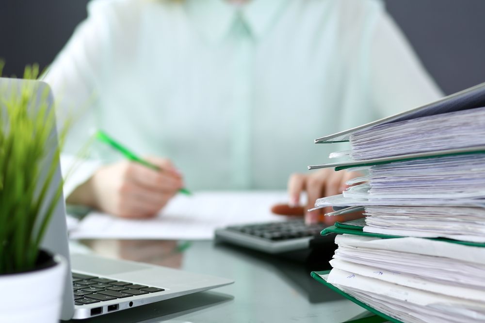 A Person in a Light Shirt Works at a Desk With a Calculator — Richardson Conveyancing In Tumbi Umbi, NSW