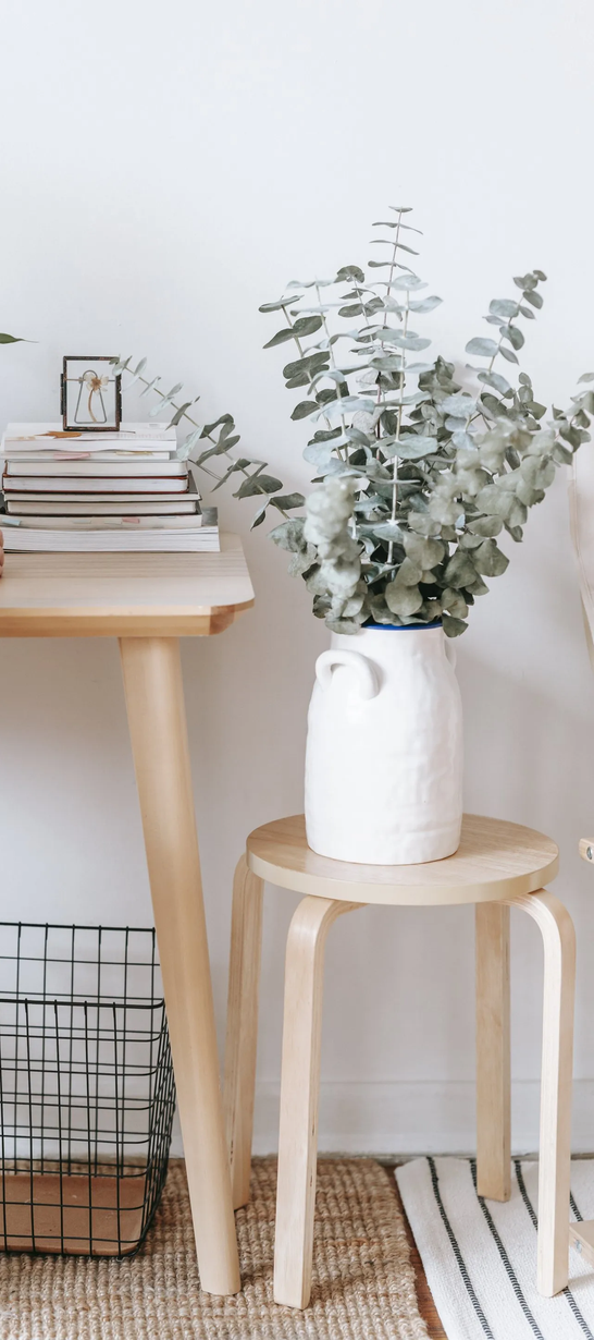 A woman is sitting at a desk with a laptop and a vase of flowers.