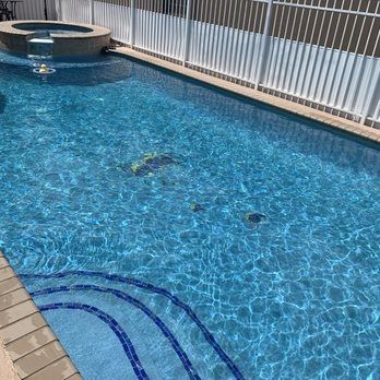 Blue swimming pool with rippled water, circular spa at the far end, and tiled deck edge in the foreground