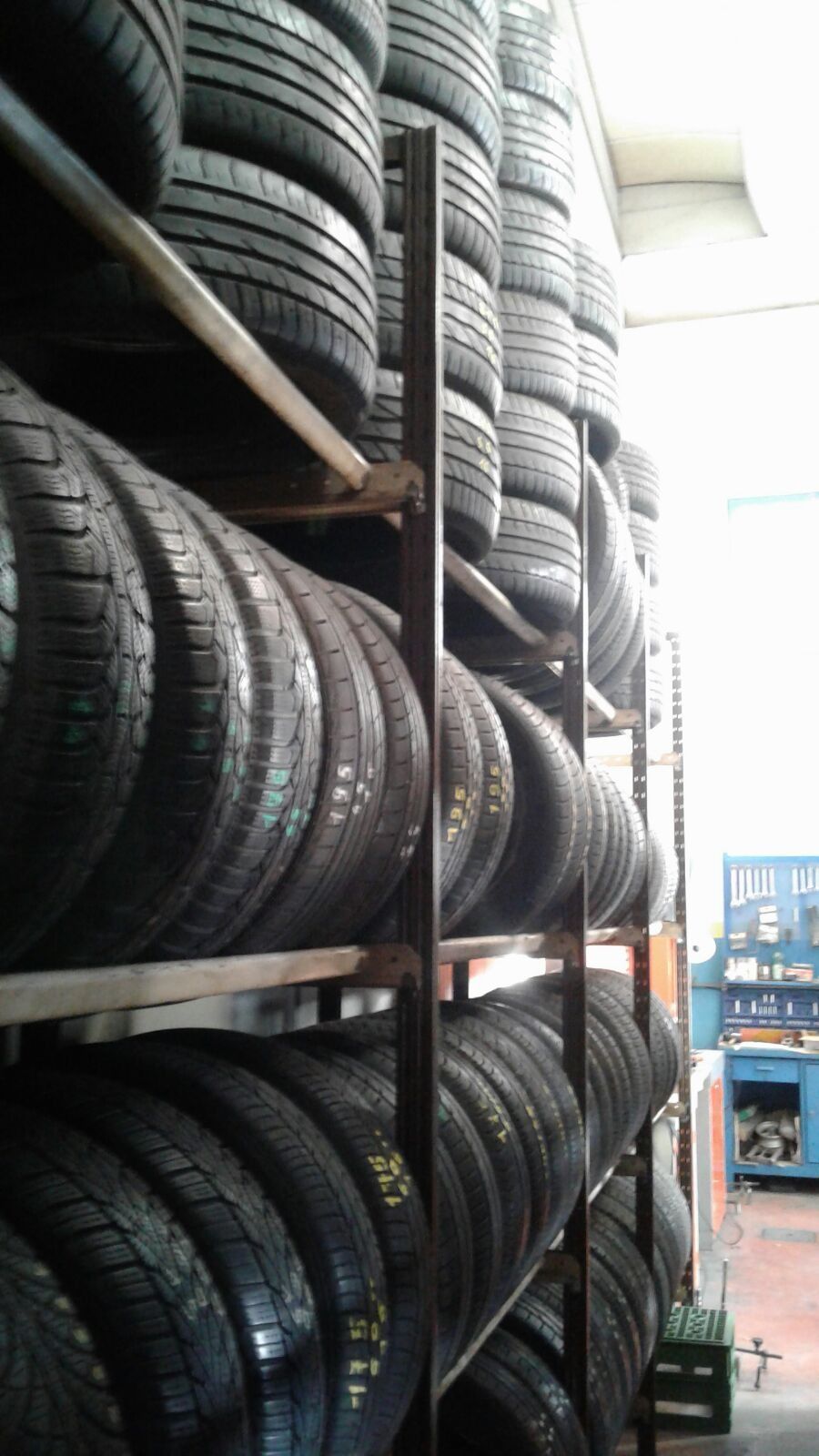 Pneumatici impilati su scaffali metallici all'interno di un negozio. File di pneumatici neri riempiono l'inquadratura.