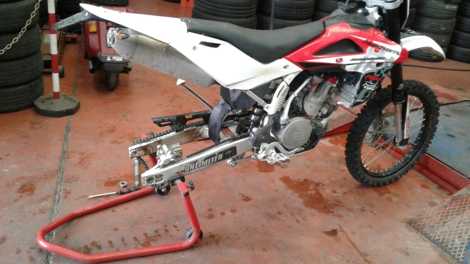 Moto da cross rossa e bianca su un supporto rosso all'interno di un negozio.