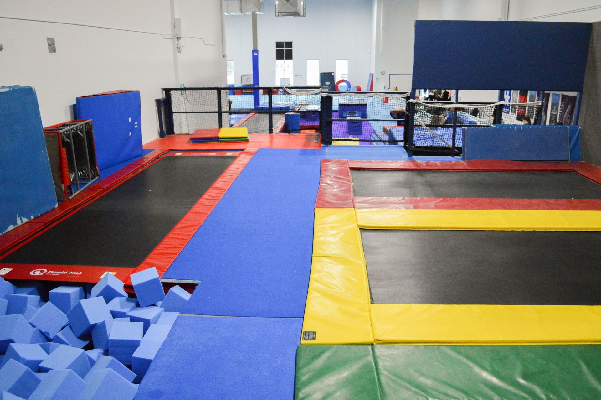 A gym with a lot of trampolines and foam cubes.