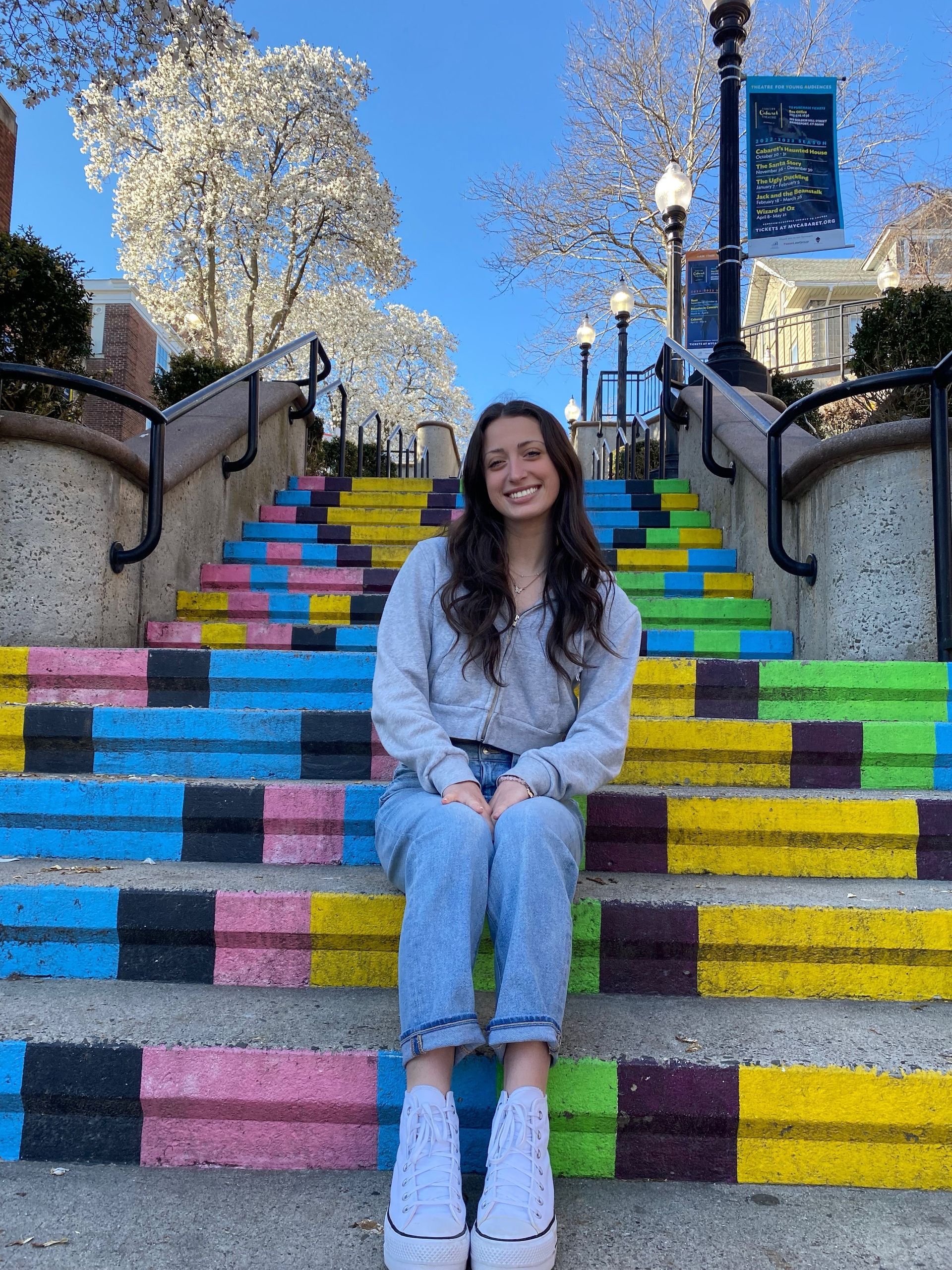 A woman is sitting on a set of colorful stairs.