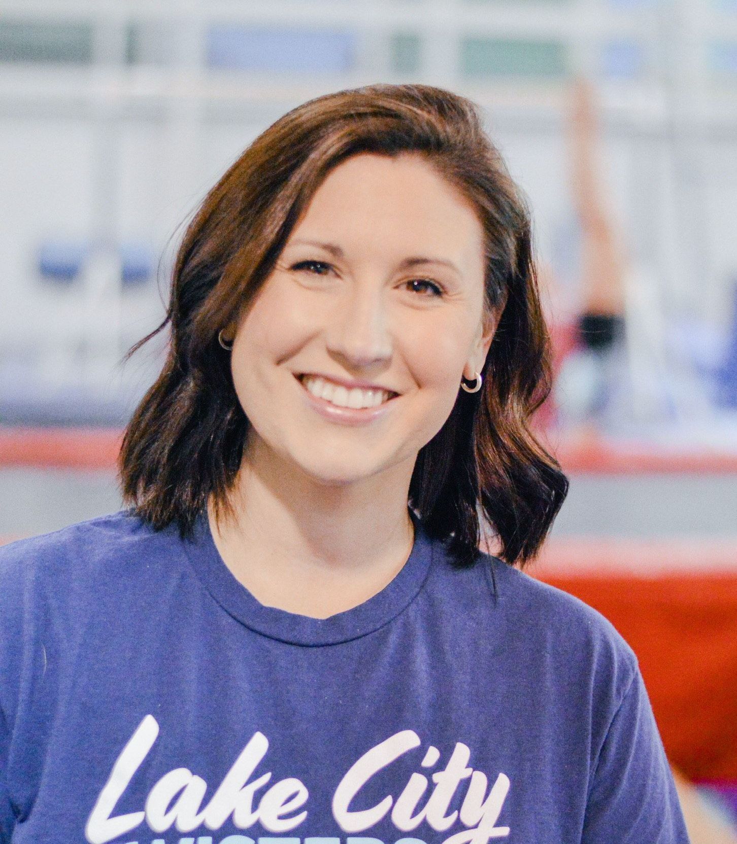 A woman wearing a blue lake city shirt is smiling for the camera.