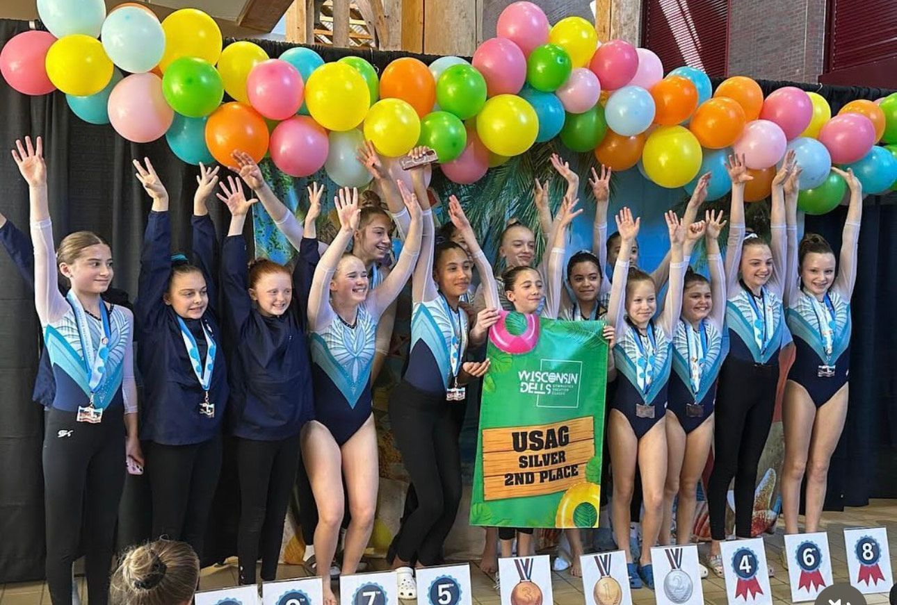 A group of young girls are posing for a picture with balloons in the background.