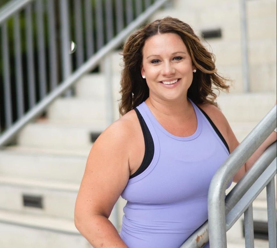 A woman in a purple tank top is leaning on a railing