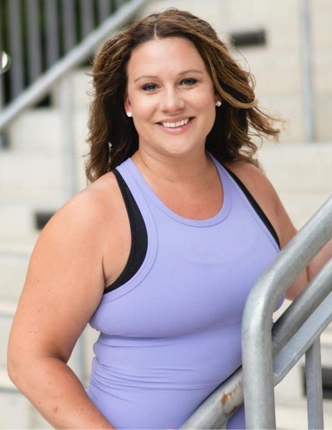 A woman in a purple tank top is leaning on a railing