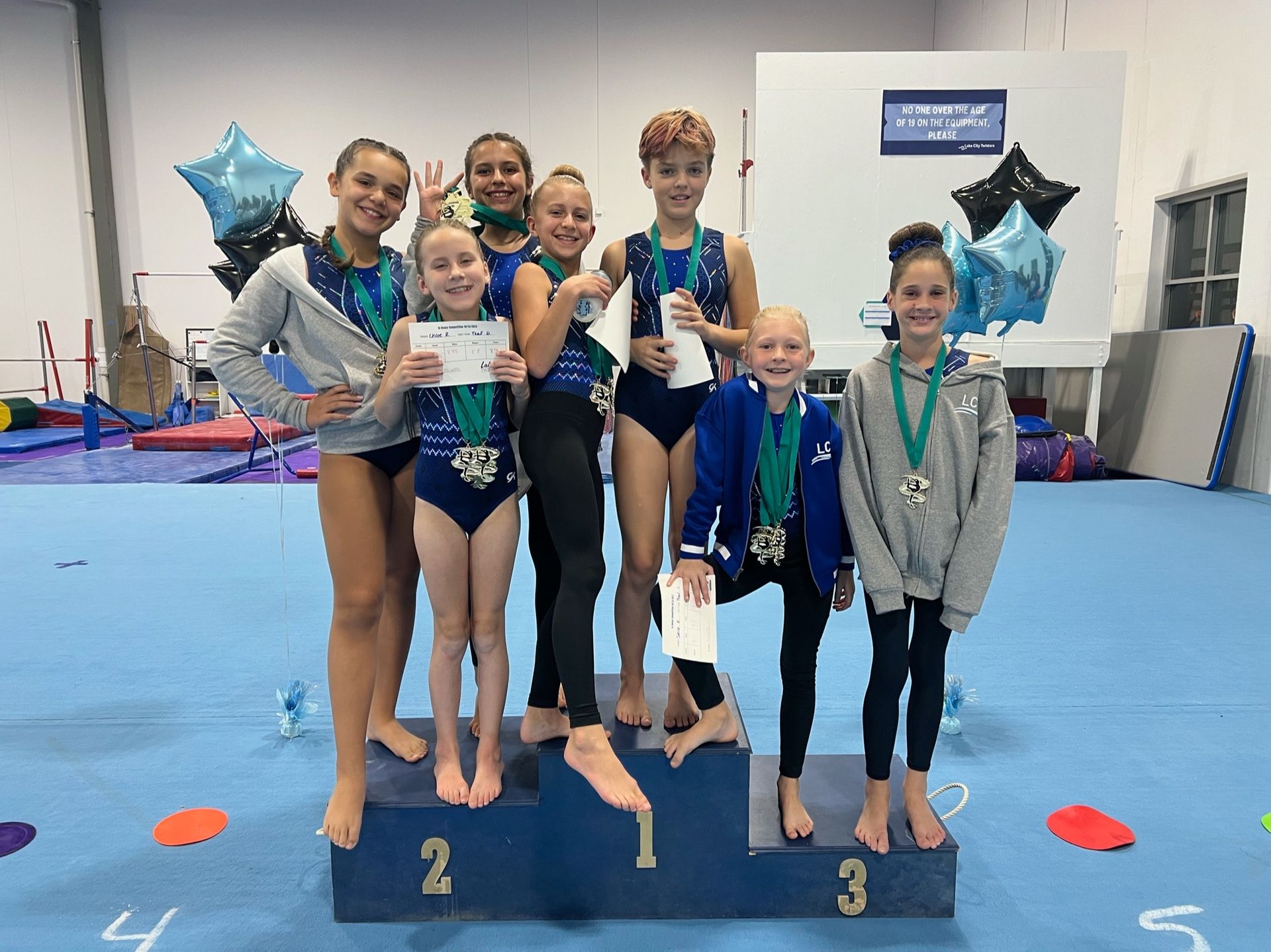 A group of young girls are standing on a podium holding medals.