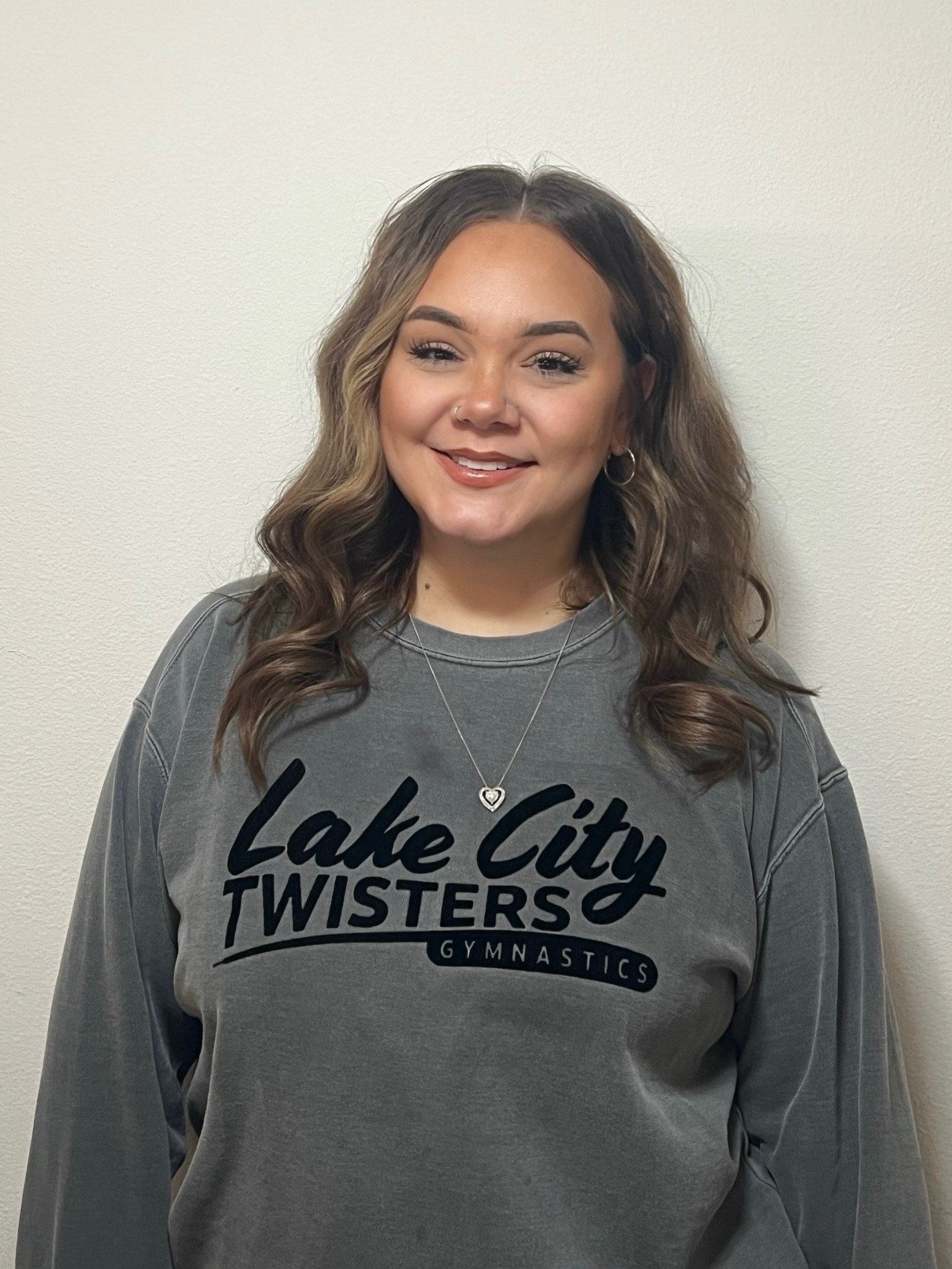 A young woman wearing a black sweatshirt is standing in a gym.