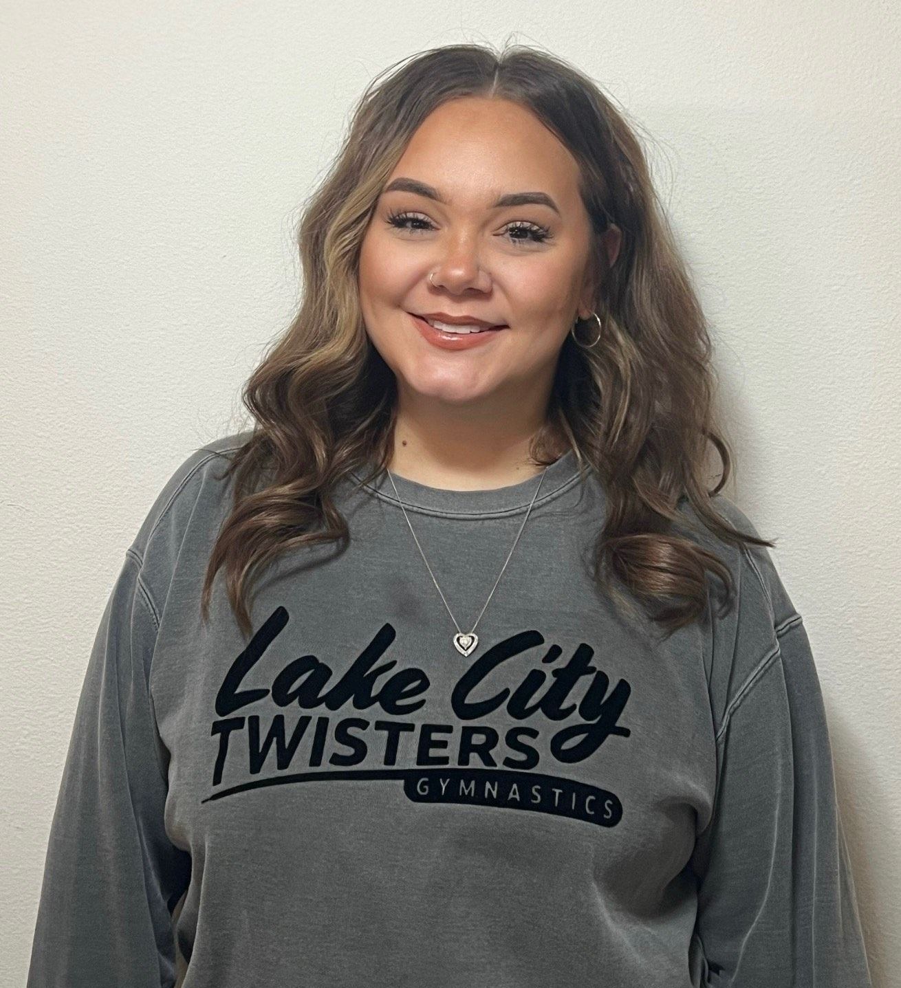 A young woman wearing a black sweatshirt is standing in a gym.