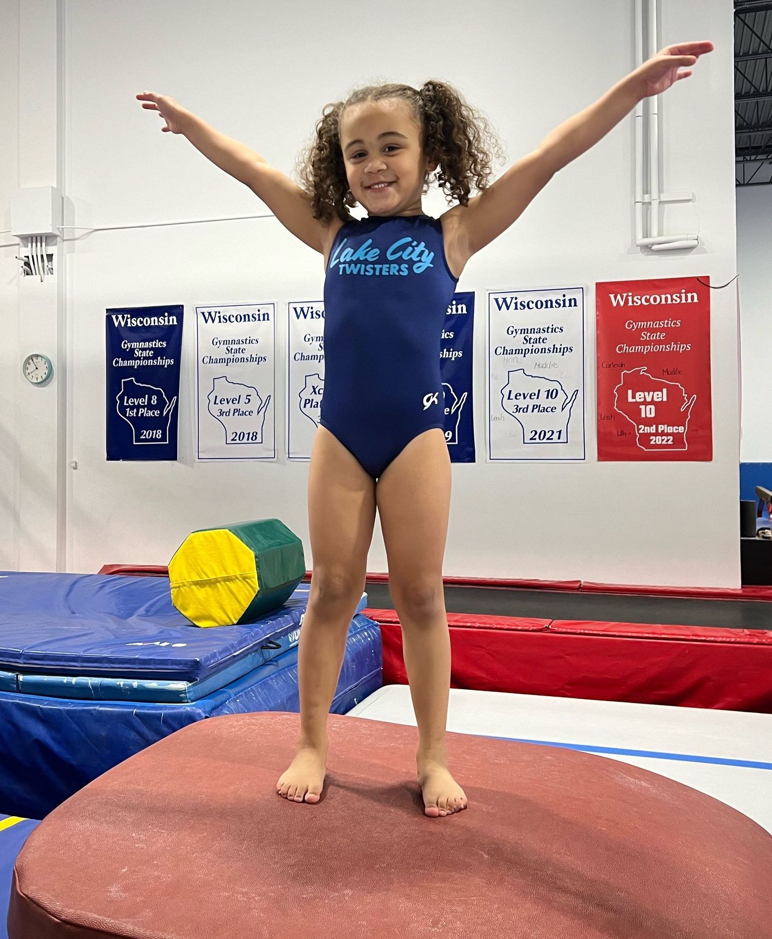 A young girl is jumping in the air in front of a wall that says gt