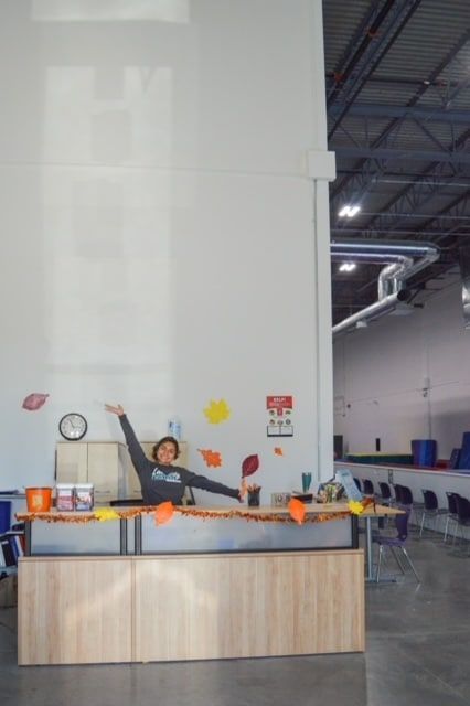 A woman is standing in front of a counter in a room with a clock on the wall