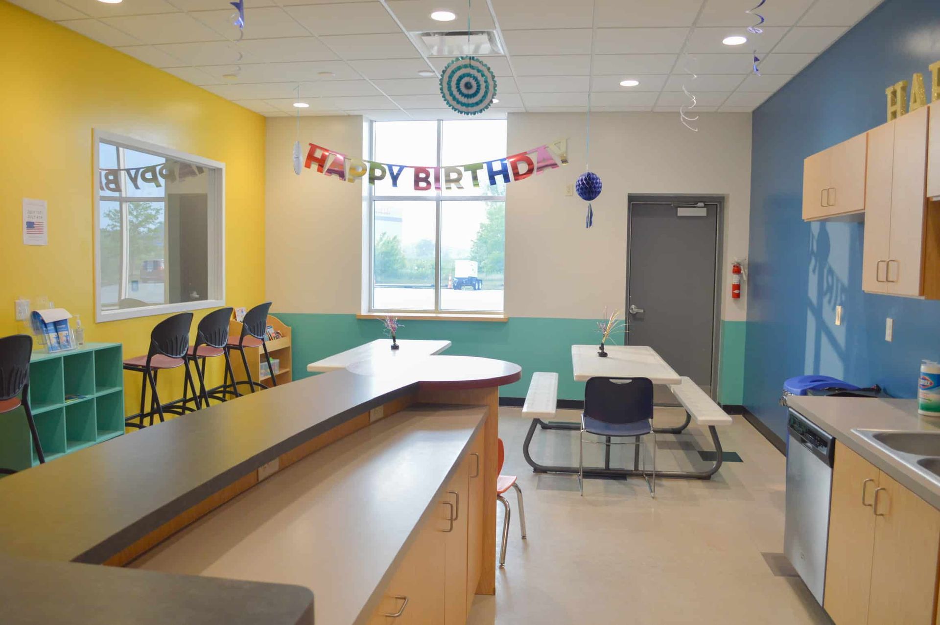 A room with tables and chairs and a sign that says happy birthday.