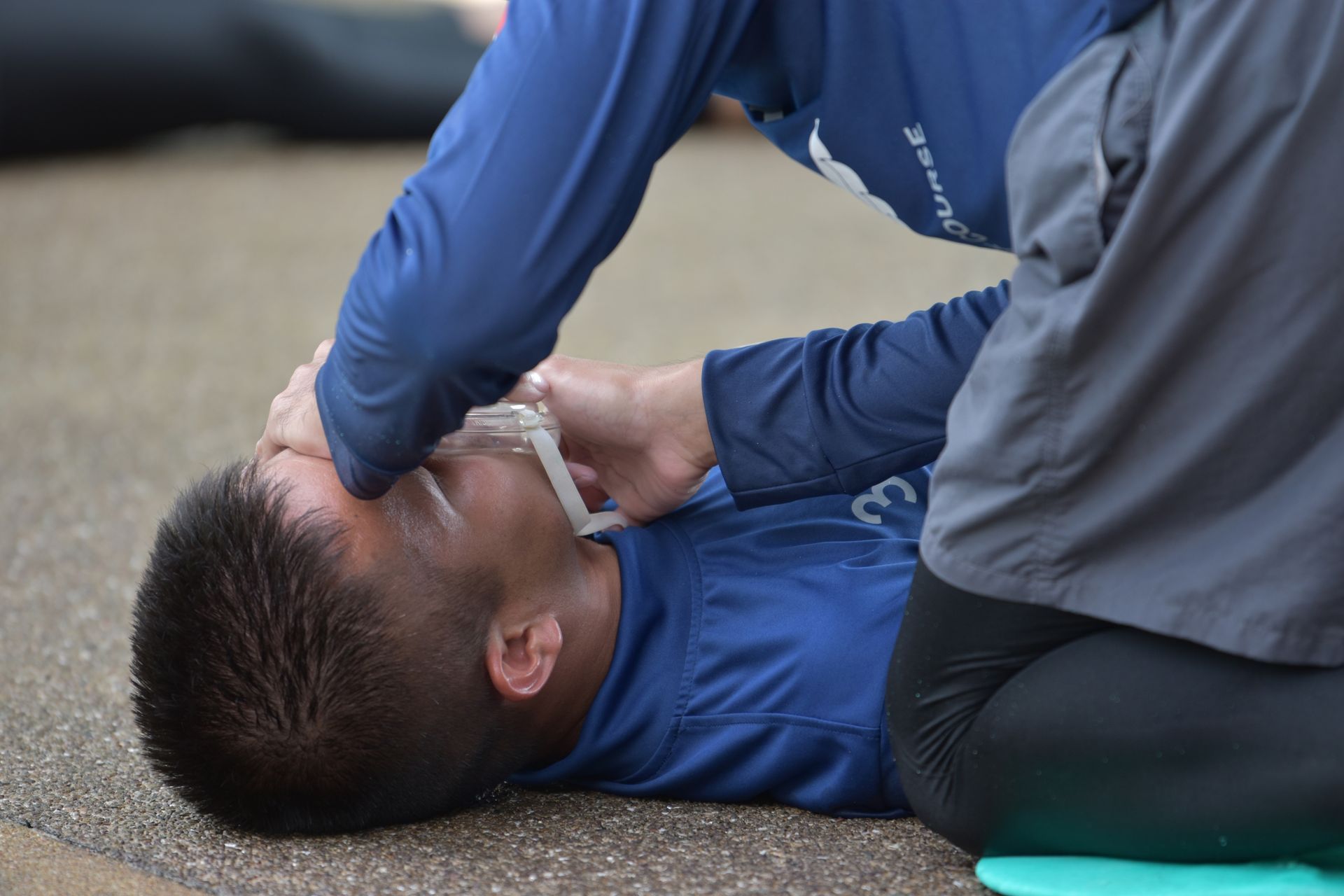 Person giving mouth-to-mouth resuscitation to another person lying on the ground.