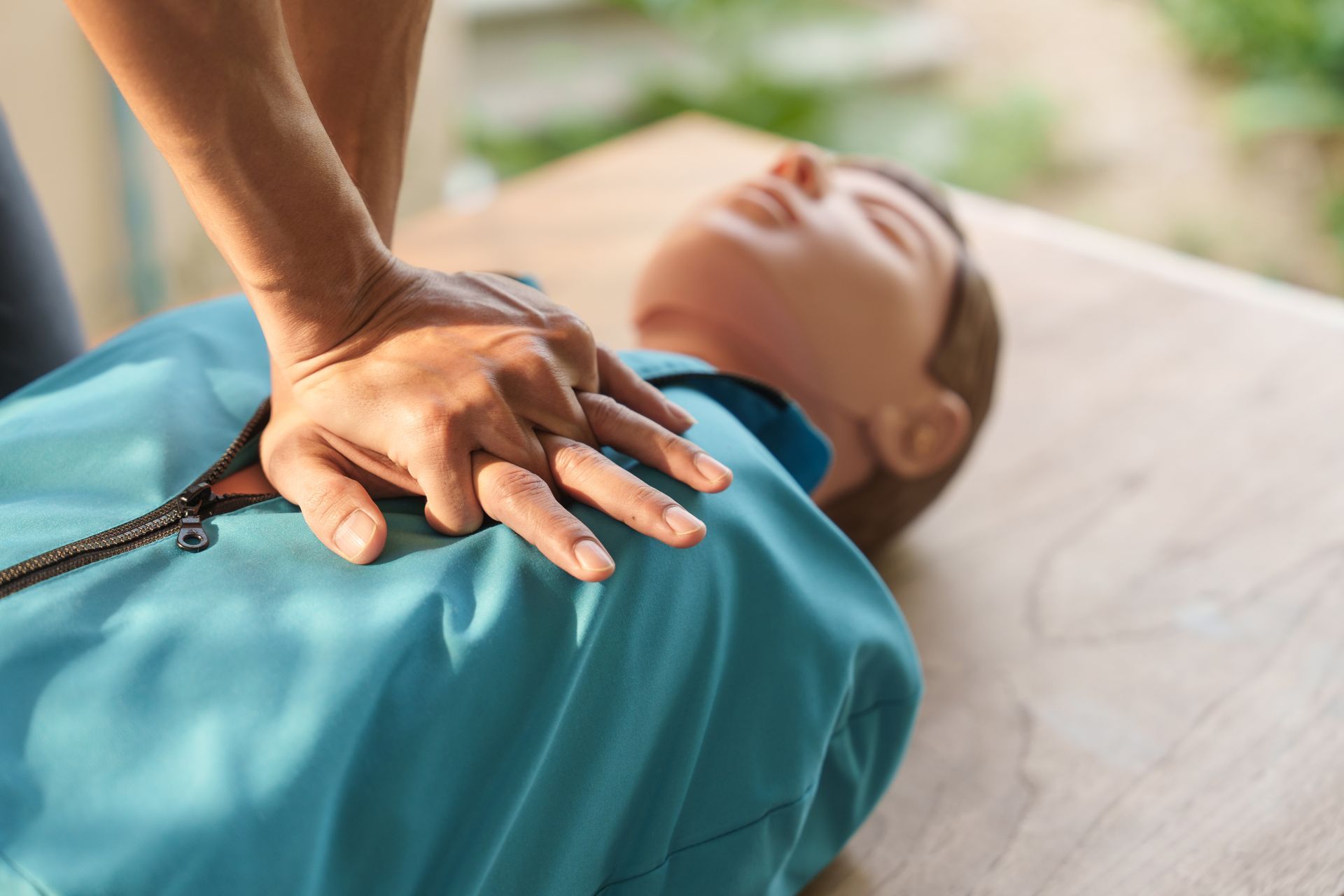Person performing CPR on a mannequin in a training setting.