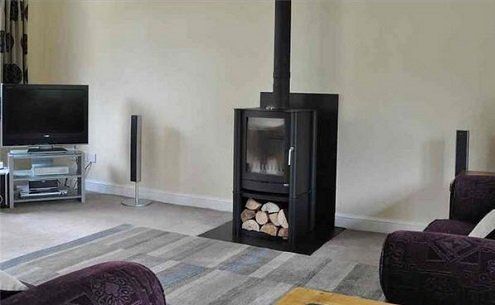 Modern wood burning stove in centre of wall