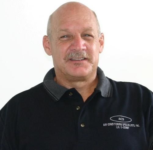 A man with a mustache, wearing a black polo shirt with an ACS Air Conditioning Specialists logo, smiles against a white wall.