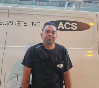 A person stands in front of a white work van with the