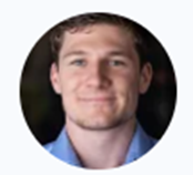 A person with short, light brown hair wearing a blue button-down shirt, framed in a circular portrait.