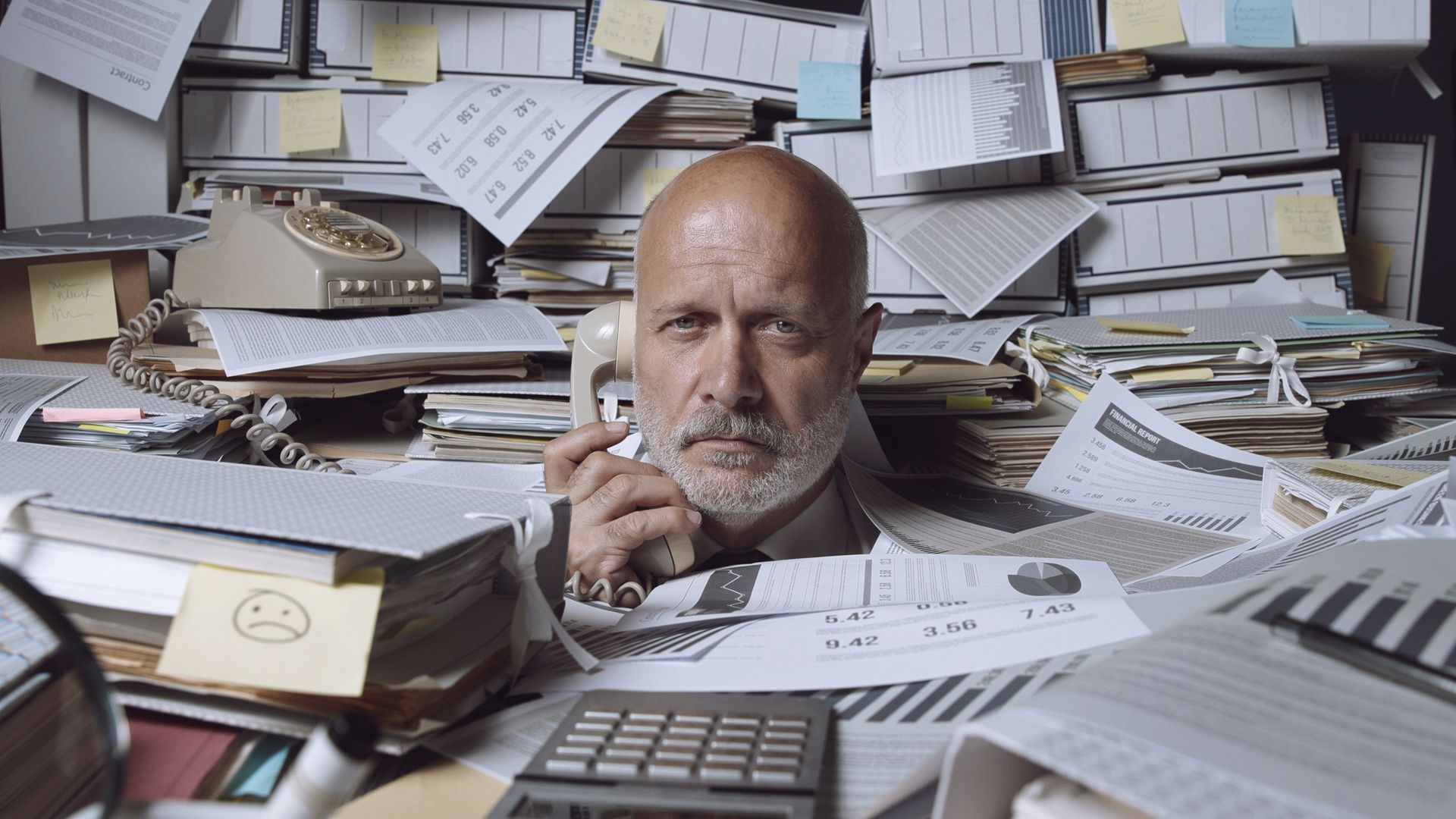 
Overwhelmed small business owner surrounded by paperwork, representing the stress of disorganized 
