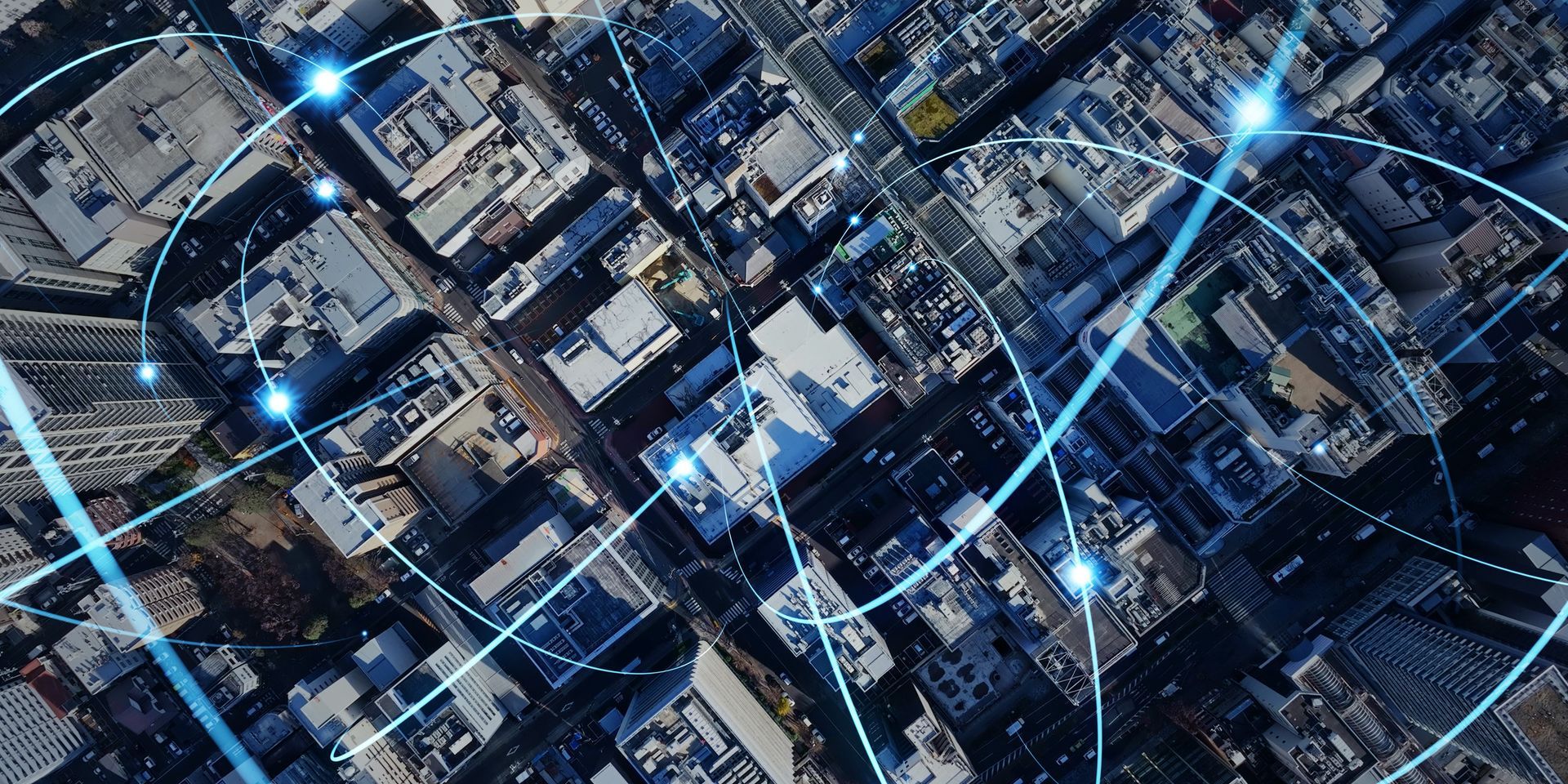 Overhead view of a city with connected blue lines and glowing nodes, representing data networks.
