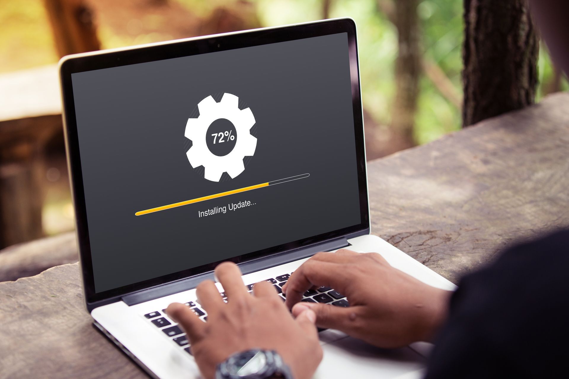 Person using a laptop outdoors, displaying a software update screen.