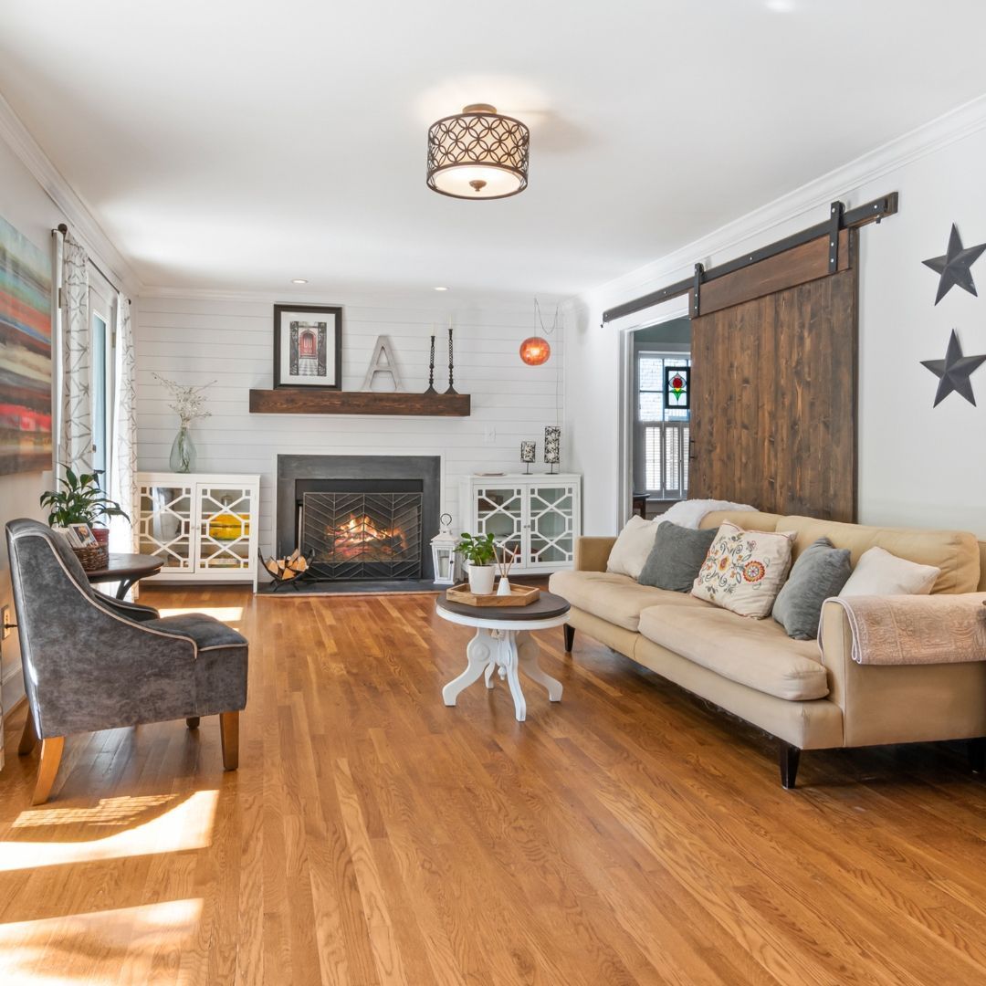 Cozy living room with wood floors, a fireplace, and a tan sofa. A wooden barn door is on the right.