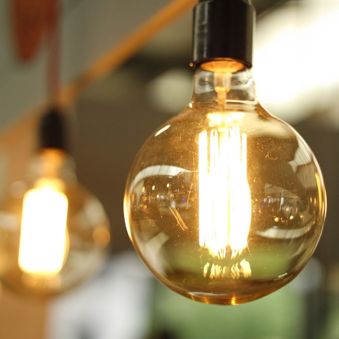 Close-up of lit, round, amber-colored light bulbs hanging from the ceiling.