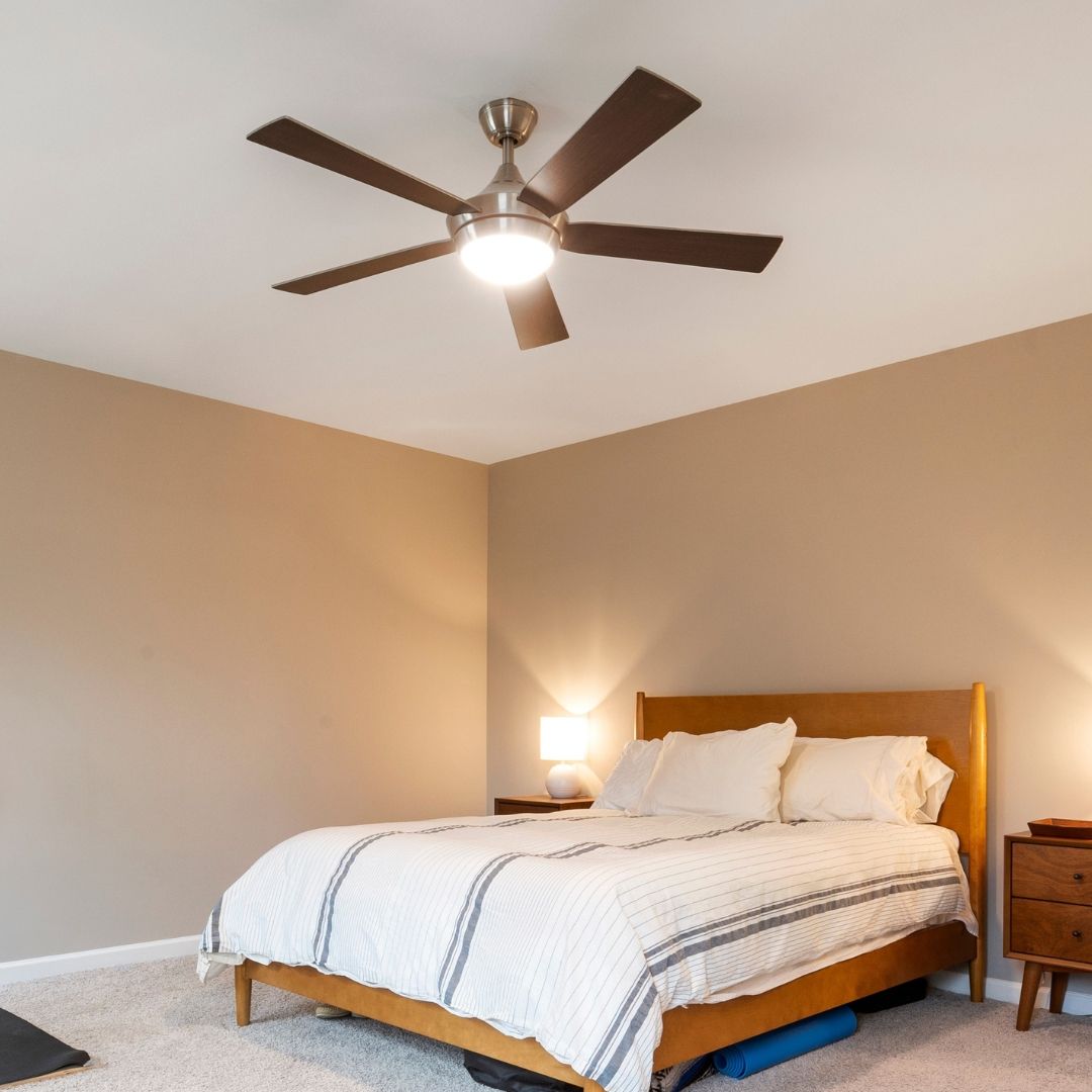Bedroom with bed, nightstands, ceiling fan, and neutral-colored walls.