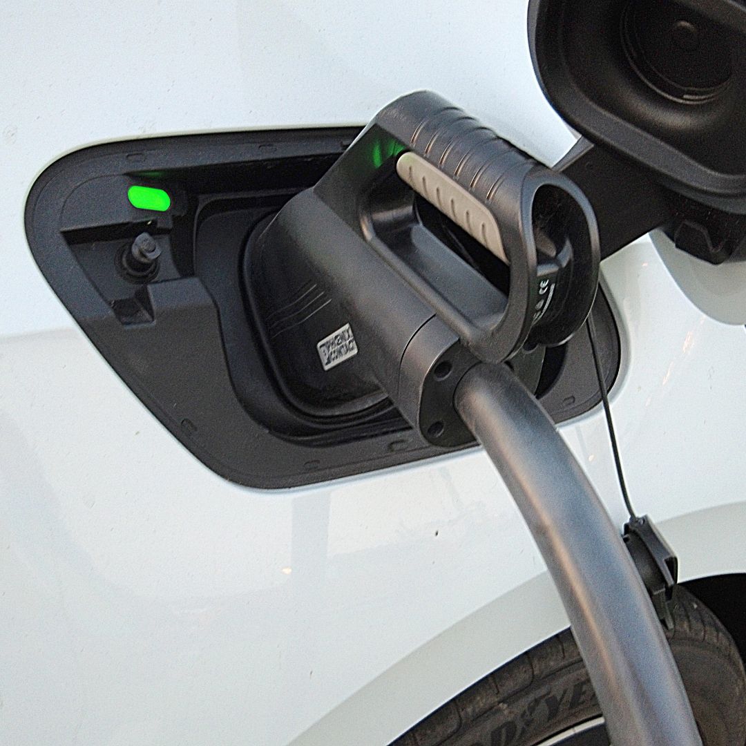 EV charging port with charging cable connected; green charging indicator.