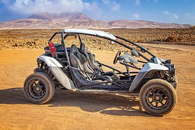 A white buggy is parked on a dirt road in the desert.