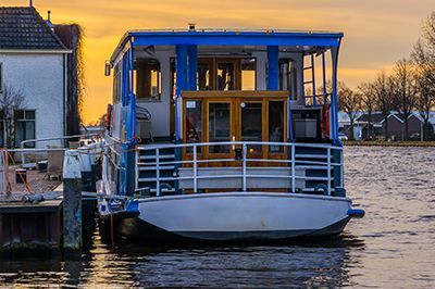 A small boat is docked in the water near a house.