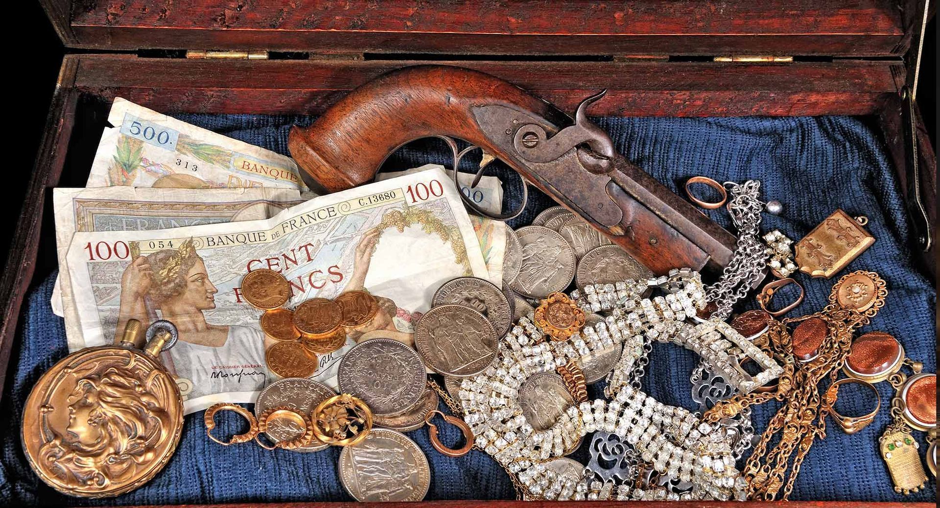 Antique paper bills, coins and pistol placed on the old box