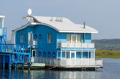 A blue houseboat is floating on top of a body of water