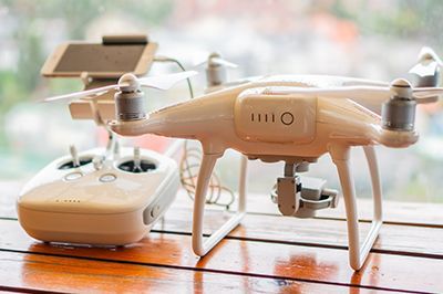 A drone and remote control are sitting on a wooden table.