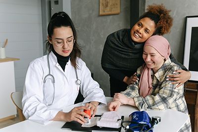 A woman is sitting at a table with a doctor and a woman with cancer.