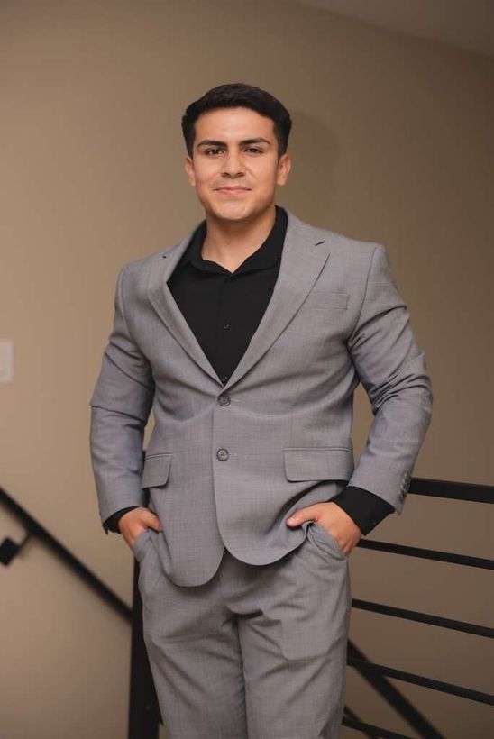 A woman is sitting at a desk with a laptop and a vase of flowers.