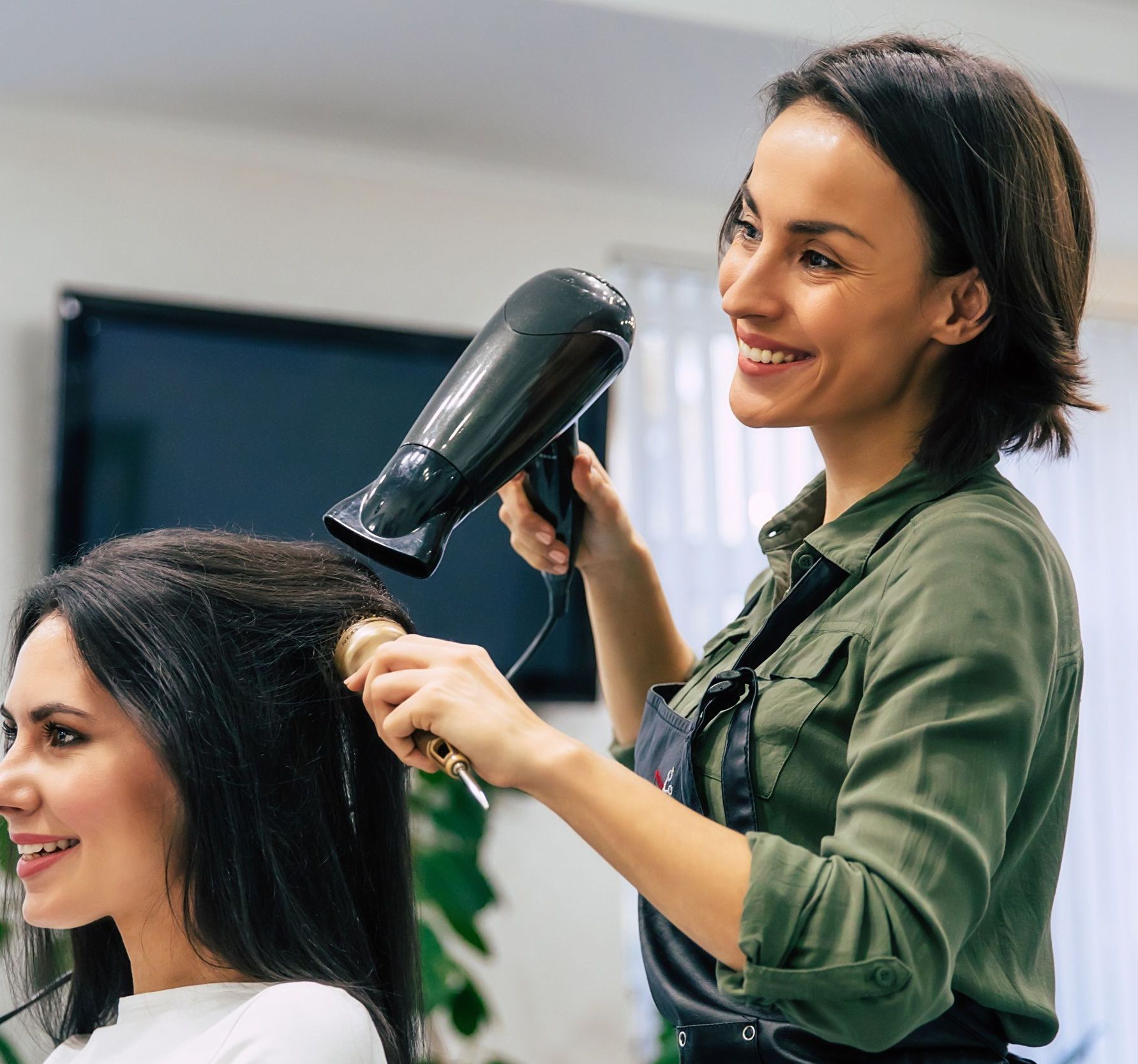 A woman is getting her hair blow dried by a hairdresser