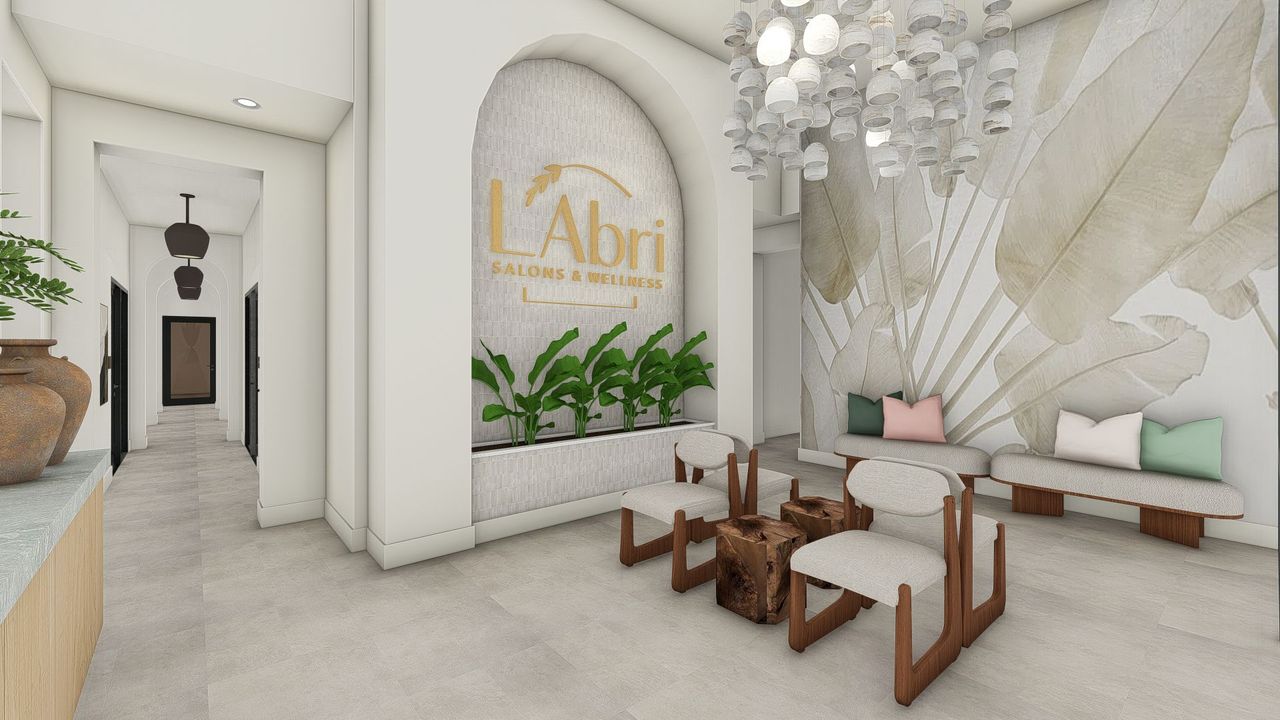 Elegant lobby with chairs, coffee bar, and L'Abri logo. Bright, airy space with plants and light fixtures.