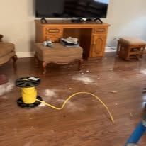 A living room with hardwood floors , a desk and a television.