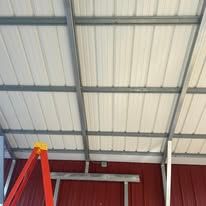 A ladder is sitting under a metal roof in a building.