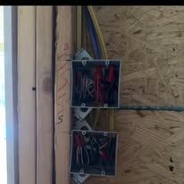 Two electrical boxes are hanging on a wooden wall.