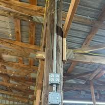 A wooden pole with electrical wires hanging from it.